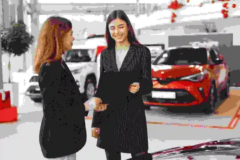 Two women standing in front of cars